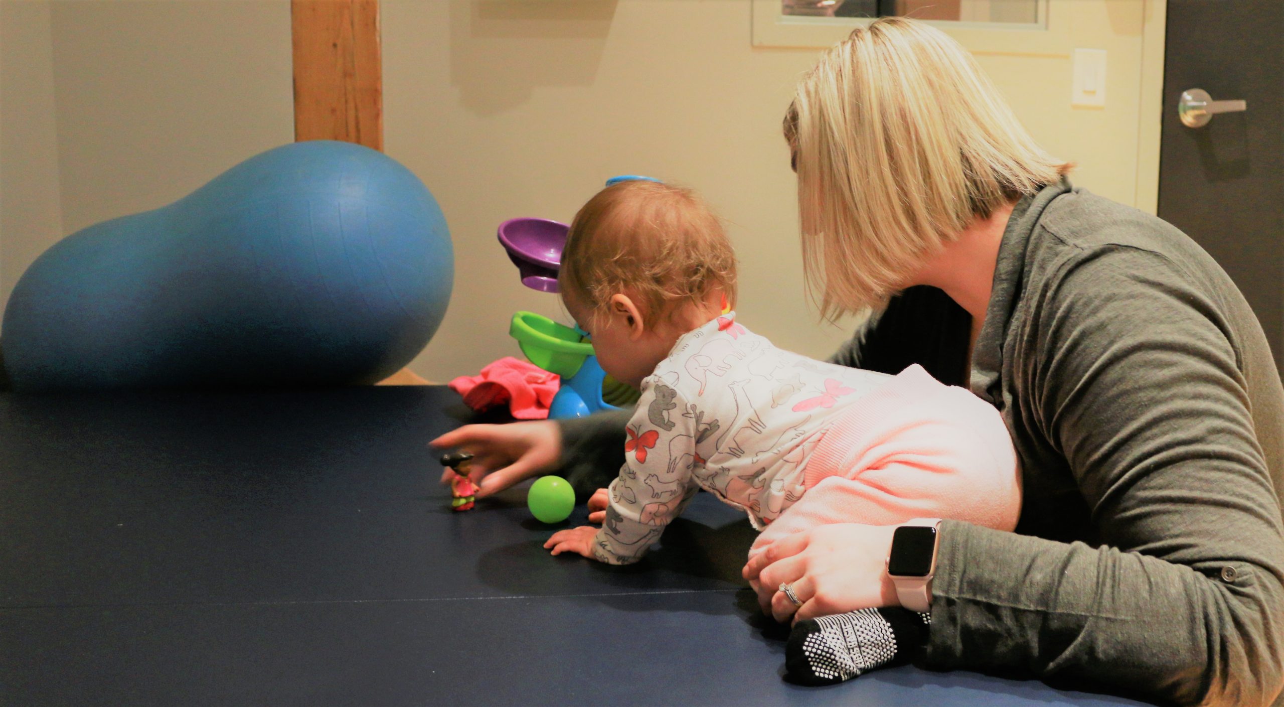 Physical therapist applying pediatric physical therapy treatment to a baby to help with crawling.