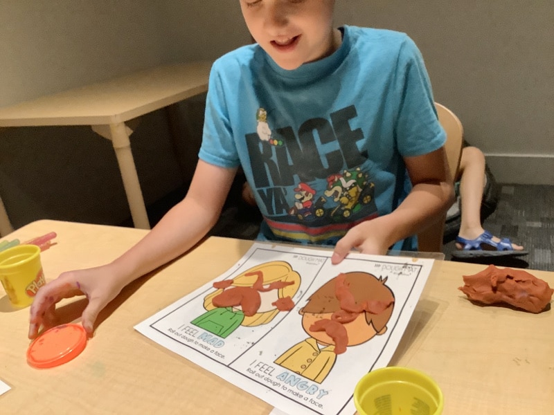 Child creating emotional faces out of playdough