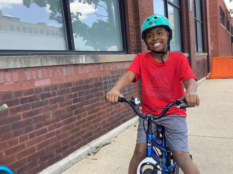 Child smiling while riding his bike for a therapy activity. Child smiling while riding his bike for a therapy activity.