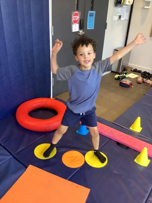 Child lifting his arms in a sensory gym for physical activity.