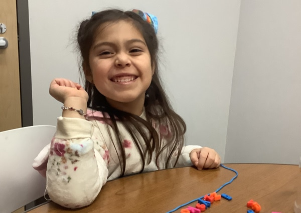 child smiling and working on a project at a table